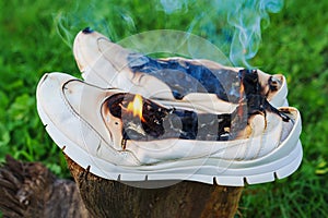 Burning leather sports shoes. Sneakers or gym shoes on fire stand on the Stump.