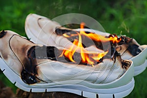 Burning leather sports shoes. Sneakers or gym shoes on fire stand on the Stump.