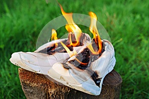 Burning leather sports shoes. Sneakers or gym shoes on fire stand on the Stump.