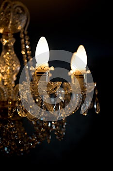 A burning light bulb on a crystal chandelier on a dark background