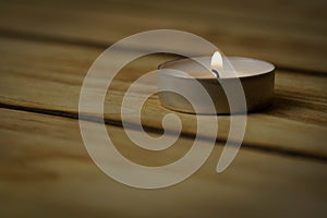 Burning lonely candle with on wood background, shot with shallow depth of field