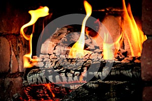 Burning long spurts of flames in fireplace on black and gray burnt logs