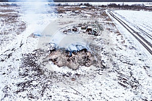 Burning manure pile at farm, air pollution and contamination, aerial shot from drone pov