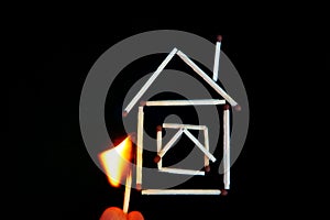 burning match near the model of a house