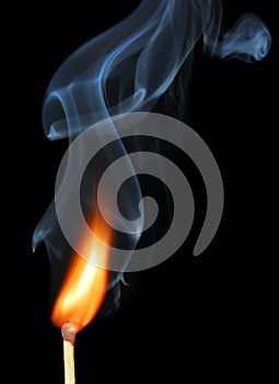 Burning match with smoke on black