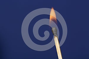 Burning match stick against blue background