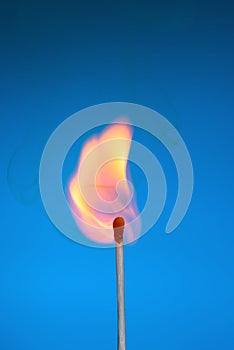 Burning match stick with fire and smoke on blue