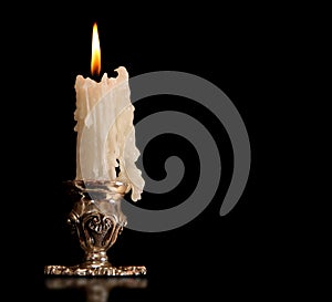 Burning old candle vintage bronze Silver candlestick. Isolated Black Background.