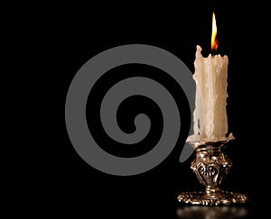 Burning old candle vintage Silver bronze candlestick. Black Background.