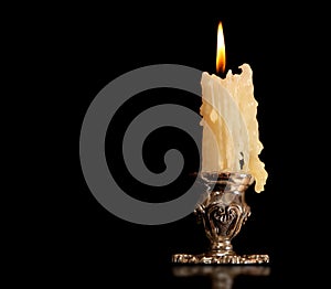 Burning old candle vintage Silver bronze candlestick. Isolated Black Background.