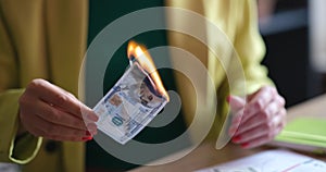 Burning one hundred dollar bill in female hands