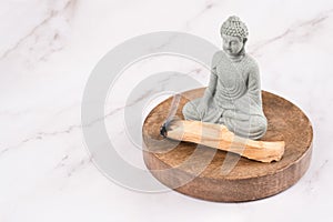 Burning palo santo sticks with Buddha statue in a meditation room on white marble background. Zen concept