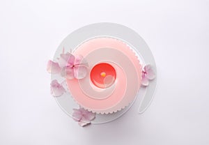 Burning pink wax candle and flowers isolated, top view