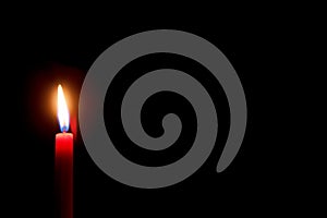 Burning red candle with black background