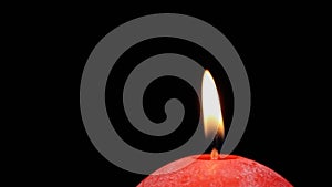 Burning red candle close up swirls on a black background