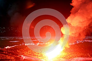 Burning red flare, flame, football hooligan. football fans lit up the lights and smoke bombs on the football pitch. Burning red fl