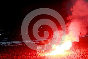 Burning red flare, flame, football hooligan. football fans lit up the lights and smoke bombs on the football pitch. Burning red fl