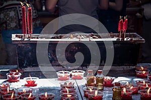 Burning red flower candle at chinese shrine for making merit. Lighting incense and candles for worship Buddha