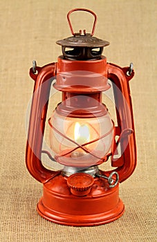 Burning red oil lamp on burlap