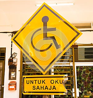 Burning of Reserved parking for Handicapped Only sign with Malaysian language `parking for handicapped only` beneath. Handicap sig