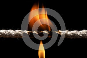 Burning rope at breaking point on black background, Risk concept