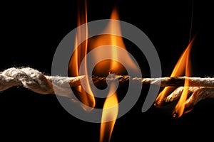 Burning rope at breaking point on black background, Risk concept