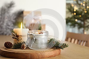 Burning scented conifer candles and Christmas decor on wooden table indoors. Space for text