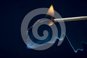 Burning and smoking wooden match on dark background