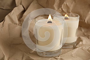 Burning soy candles with wooden wicks on crumpled kraft paper