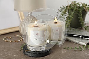 Burning soy candles with wooden wicks and decor on grey table