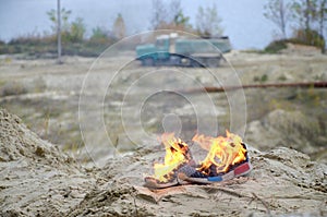 Burning sports sneakers or gym shoes on fire stand on sandy beach coast. Athlete burned out. Physical exertion during training