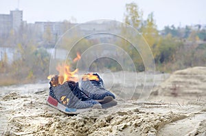 Burning sports sneakers or gym shoes on fire stand on sandy beach coast. Athlete burned out. Physical exertion during training