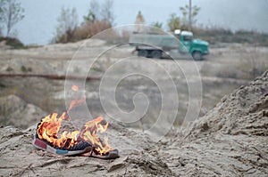 Burning sports sneakers or gym shoes on fire stand on sandy beach coast. Athlete burned out. Physical exertion during training