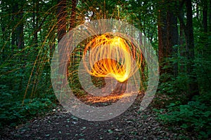 Burning steel wool spinned in the forest. Showers of glowing sparks from spinning steel wool