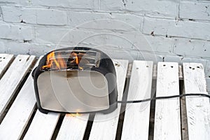 Burning toaster. Toaster with two slices of toast caught on fire over white background