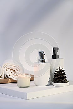 Burning wax candle, towels and soap bottles on white background.