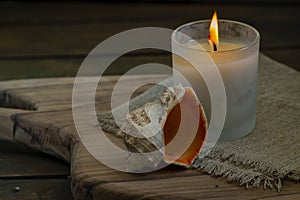 Burning white candle light on old dark wooden table background burlap sack Halloween Aromatherapy smoke rustic cutting board