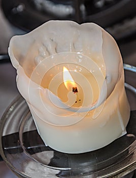 Burning white candle, melted wax, close up flame photo