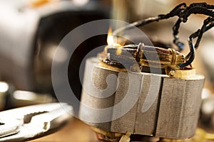 Burning wires on the details of an electrical appliance on a wooden table in a repair shop. Power tool repair