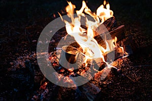 Burning wood at night. Campfire at touristic camp at nature in mountains. Flame amd fire sparks on dark abstract