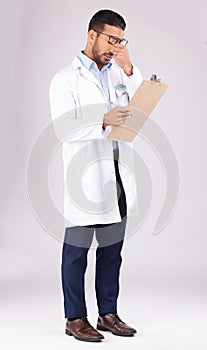 Burnout, clipboard and man doctor in a studio for a medical diagnosis or wellness treatment. Stress, headache and male