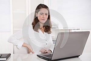 Burnout : tired businesswoman frowning at laptop - back pains or