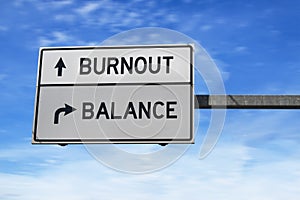 Burnout versus balance. White two street signs with arrow on metal pole. Directional road. Crossroads Road Sign, Two Arrow. Blue