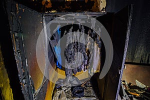Burnt apartment house interior. Burned wardrobe with clothes