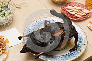 Burnt bird carcass on serving plate on dining table. Serve charred spoiled dish. Lousy housewife and bad chef. Delicious