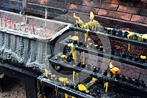 Burnt candles and incense sticks in a buddhist temple in Thailand