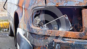 Burnt car body. Arson, short circuit. The skeleton of a burnt car. Front view of a burnt and abandoned rusty van and a