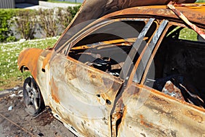 Burnt car with burnt condition in isolation on the side of the road in the wild.