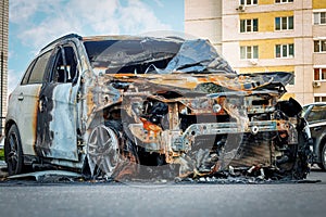 Burnt car in the courtyard of a multi-storey building. For illustration of arson, insurance claim
