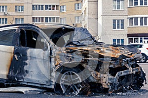 Burnt car in the courtyard of a multi-storey building to illustrate an article about a fire, banditry, an insured event, loss